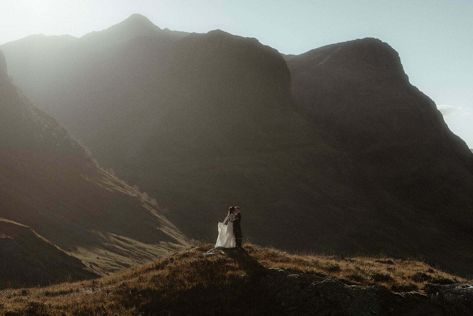 A couple dancing in the sunlight between the mountains of Glencoe after their elopement in Scotland