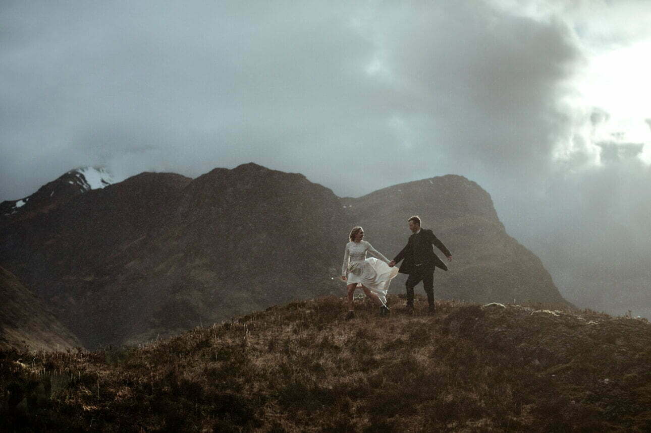 eloping in Scotland bride and groom running in the rain in the mountains of Glencoe
