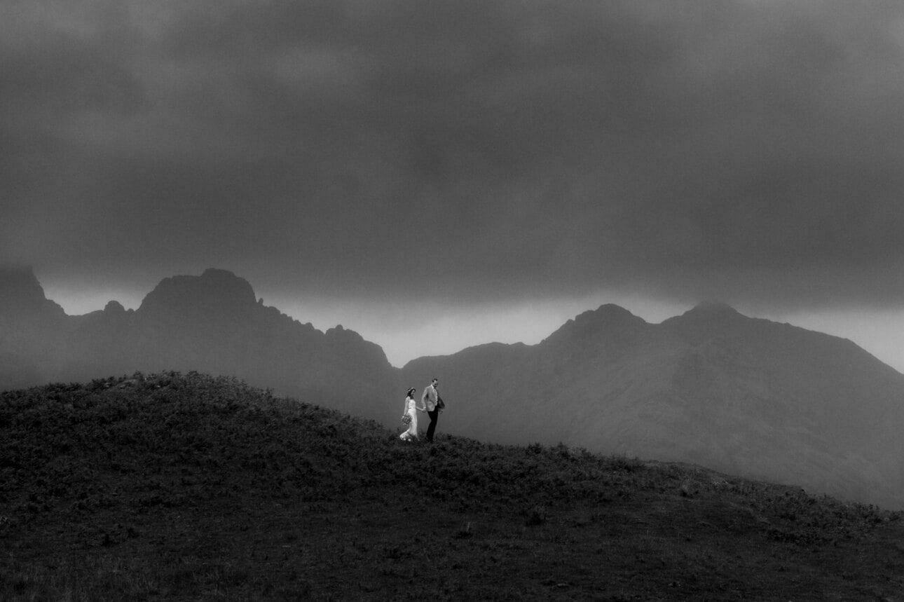 Scottish mountain elopement couple walking on isle of Skye during their wedding with blacken in the background and the Cuillin Hills