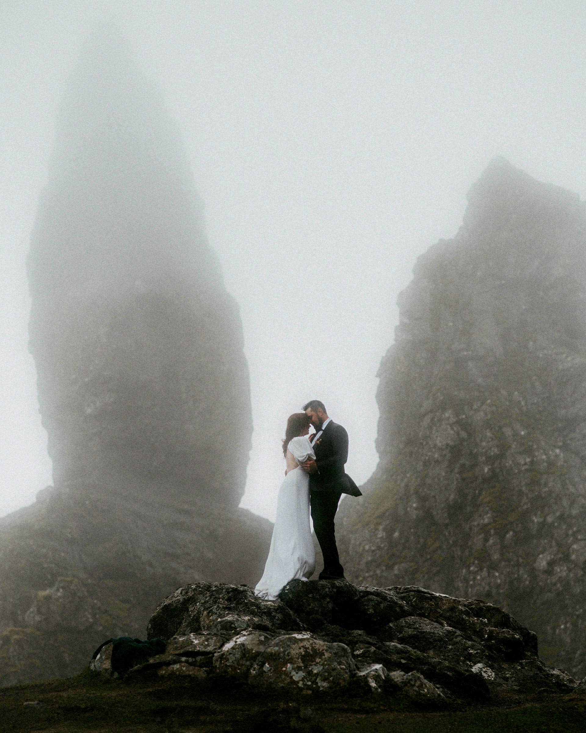 bride and groom kissing next to the old man of storr mountain on isle of skye