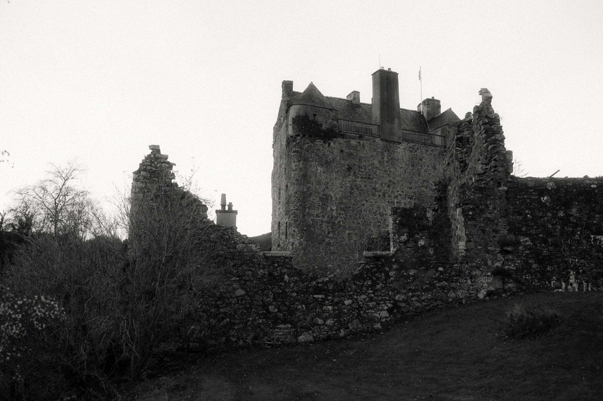 black and white image of neidpath castle on the day of a wedding