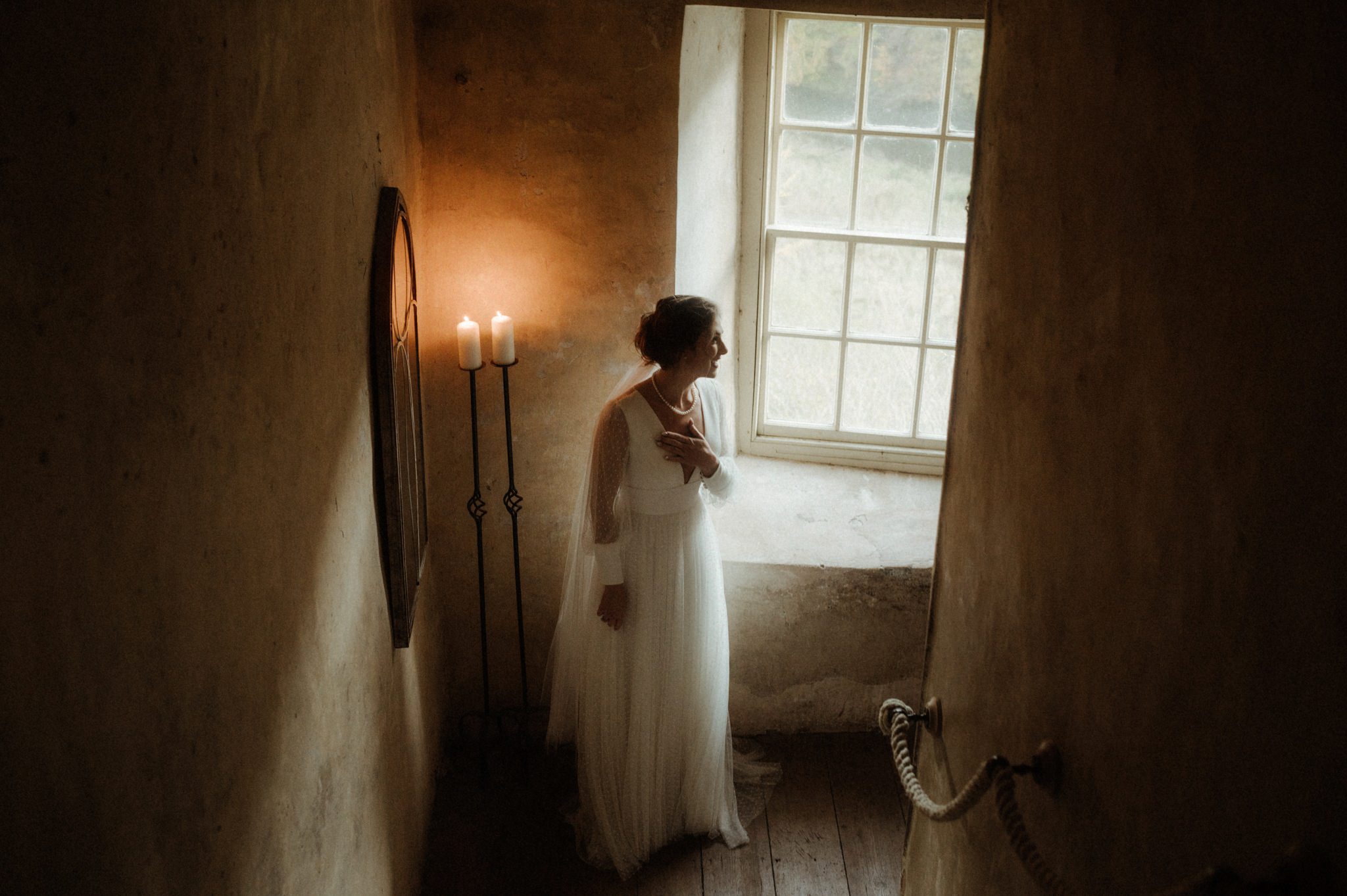 bride looking out of a window in neidpath castle with natural light during her scotland elopement