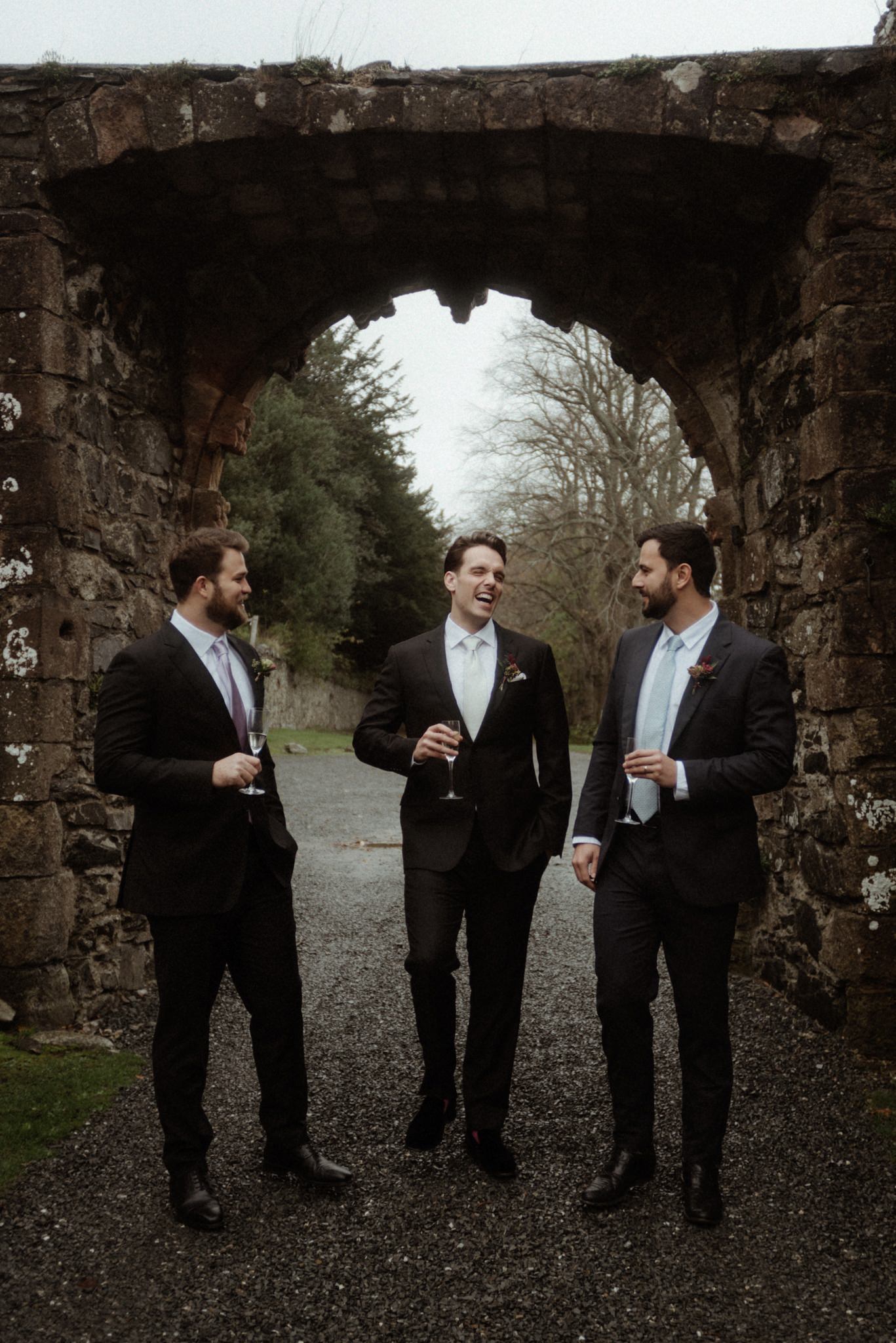 scottish borders elopement groom and groomsmen laughing outside the castle of neidpath