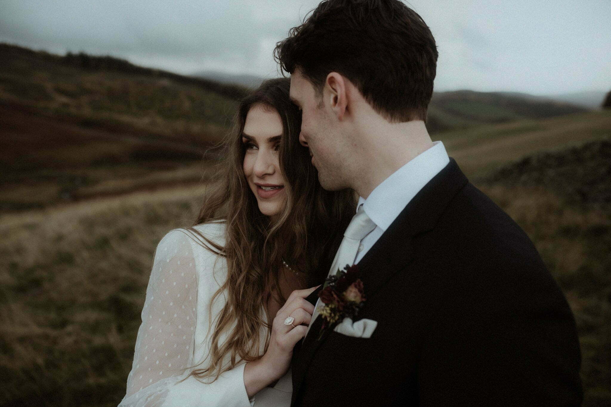 scotland elopement in the scottish borders couple standing in the hills with trees and mountains behind