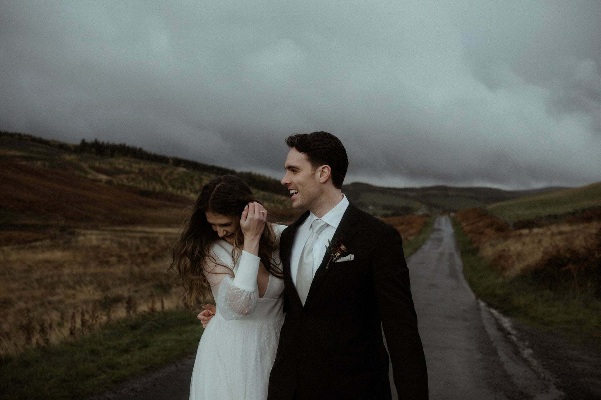 scotland elopement in the scottish borders couple dancing on the road with hills and trees behind