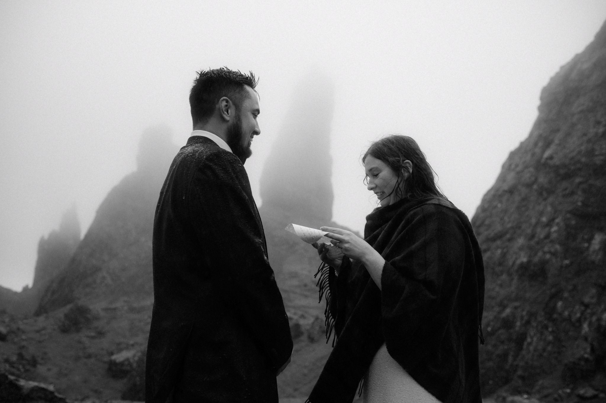 A wedding taking place in Scotland outdoors in the rain with Bride and groom reading vows near the Old man of Storr on Skye