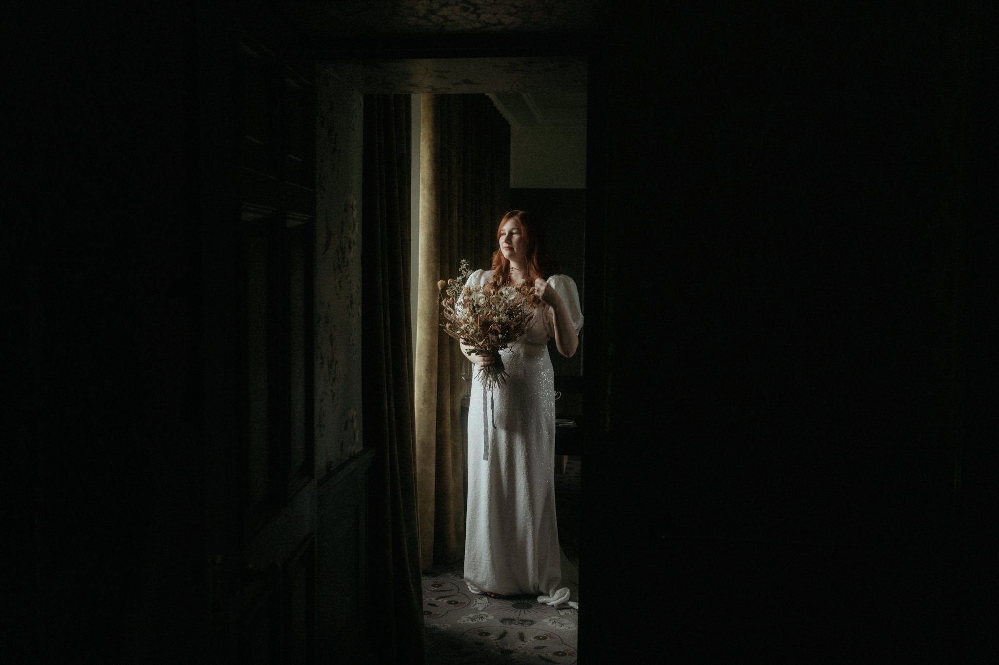 bride standing at a window at Monkstadt 1745 during an elopement