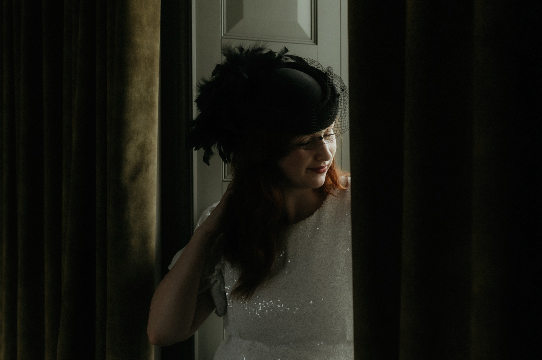 elopement in Scotland bride wearing a vintage hat whilst standing in a window