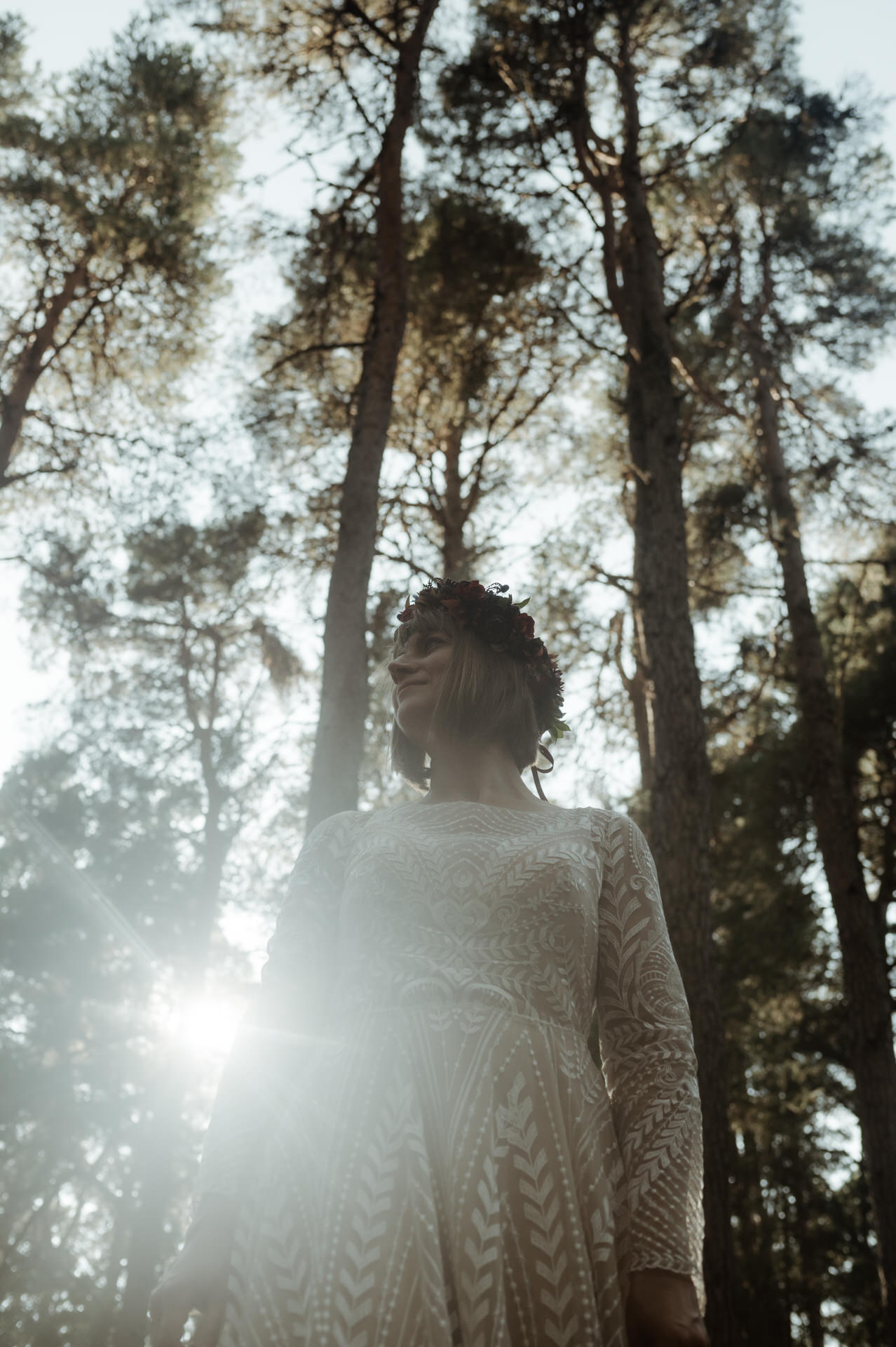 Bride shot from below into the sunlight with trees behind her in the cairngorms