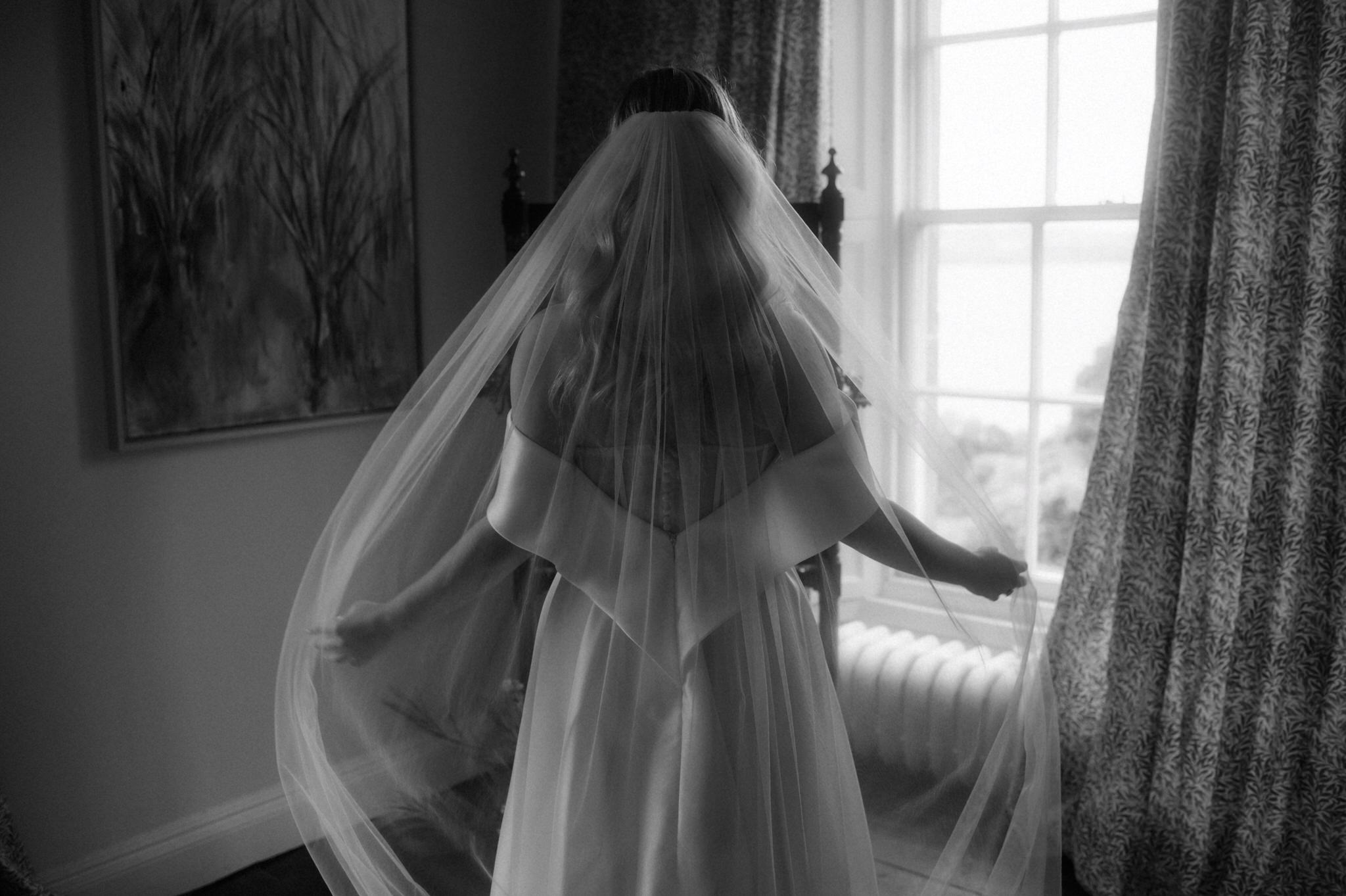 bride in dress and veil standing next to window in a Scottish castle