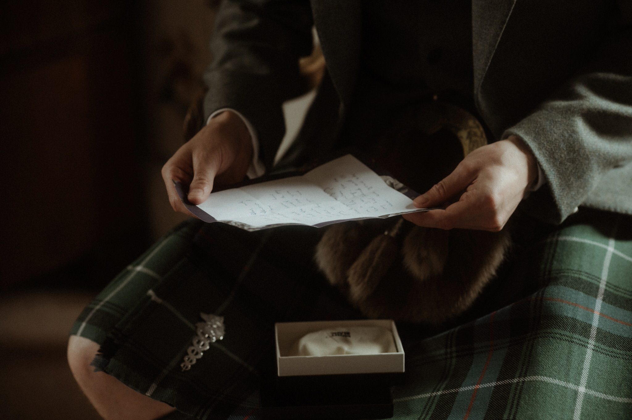 groom getting ready for his castle wedding in scotland at birkhill putting on his kilt and jacket