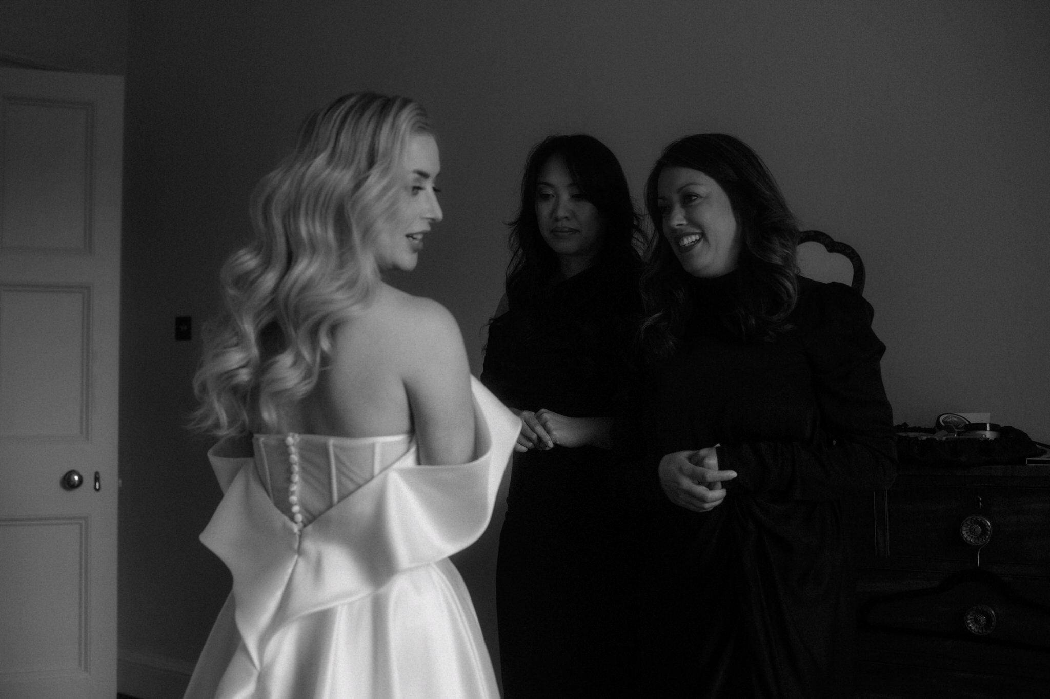 black and white picture of bride getting ready for her wedding in Scotland at Birkhill House with her bridesmaids laughing
