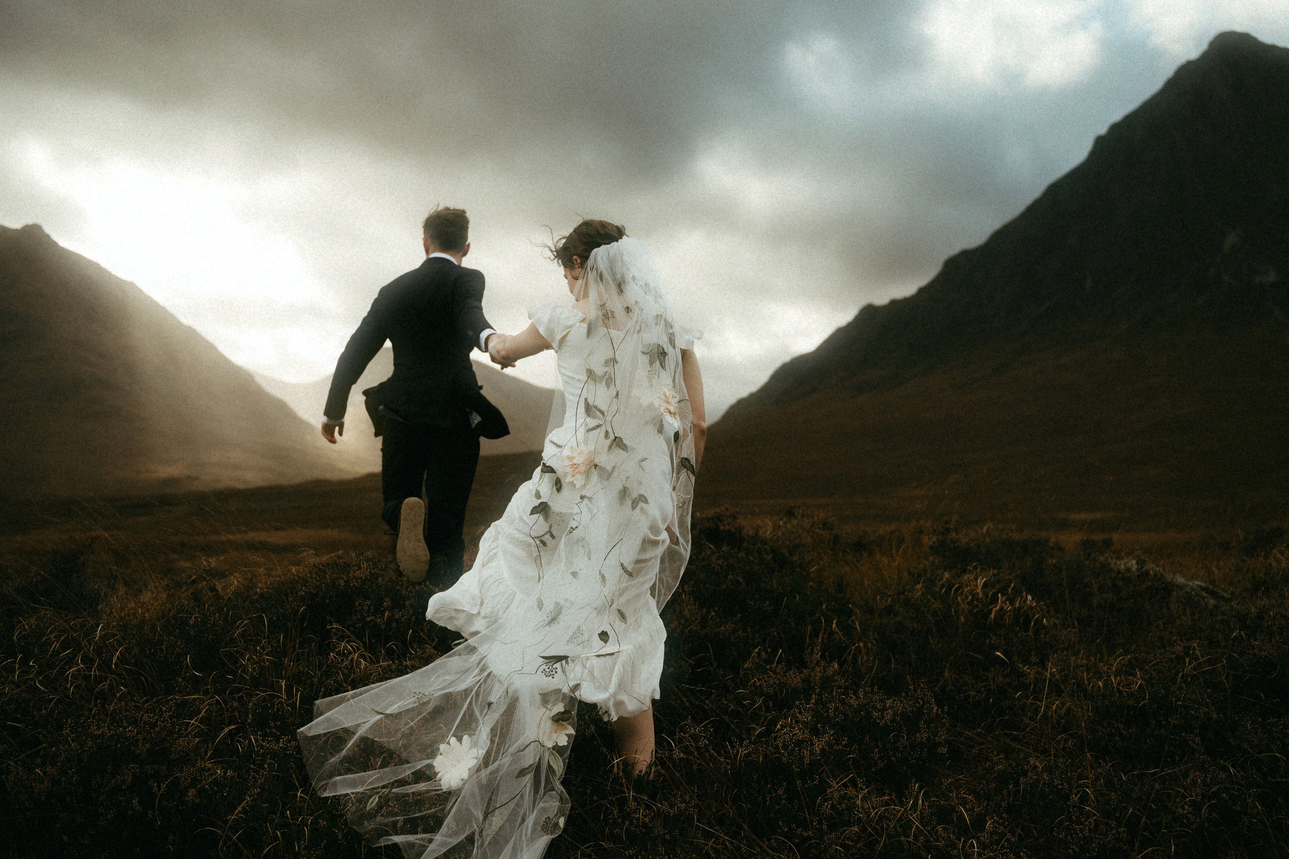 Scotland elopement in Glencoe couple running in the light towards buachaille Etive more mountain
