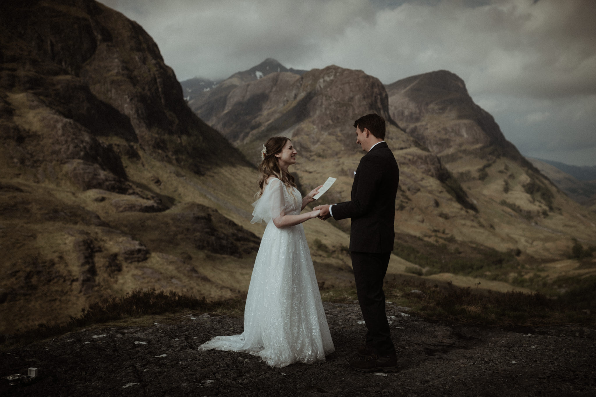 elopement ceremony in scotland in glencoe bride and groom reading vows in front of the Three Sisters mountains