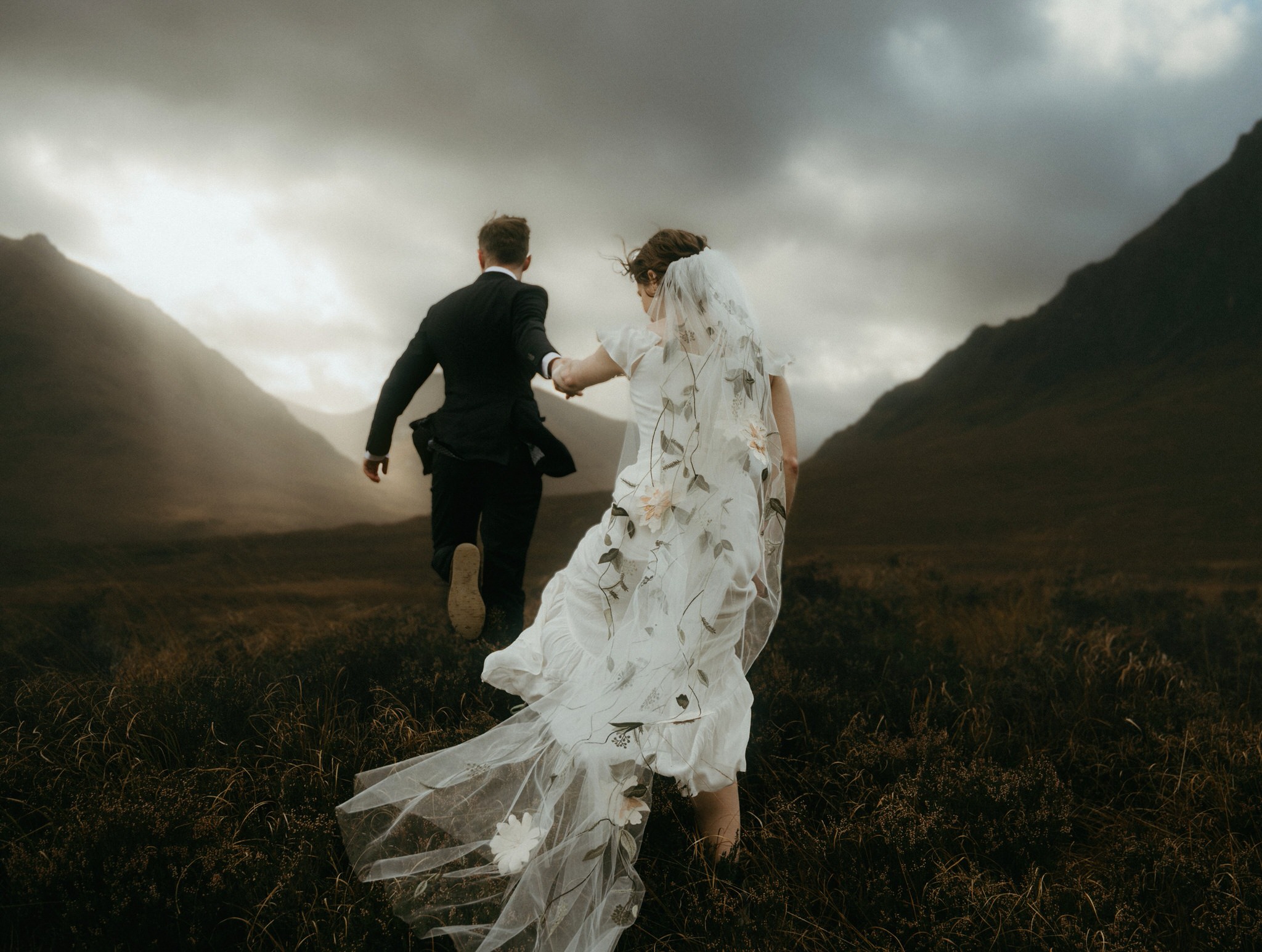 Glencoe elopement photographer Sean bell with a couple running in the Glencoe mountains into the afternoon light