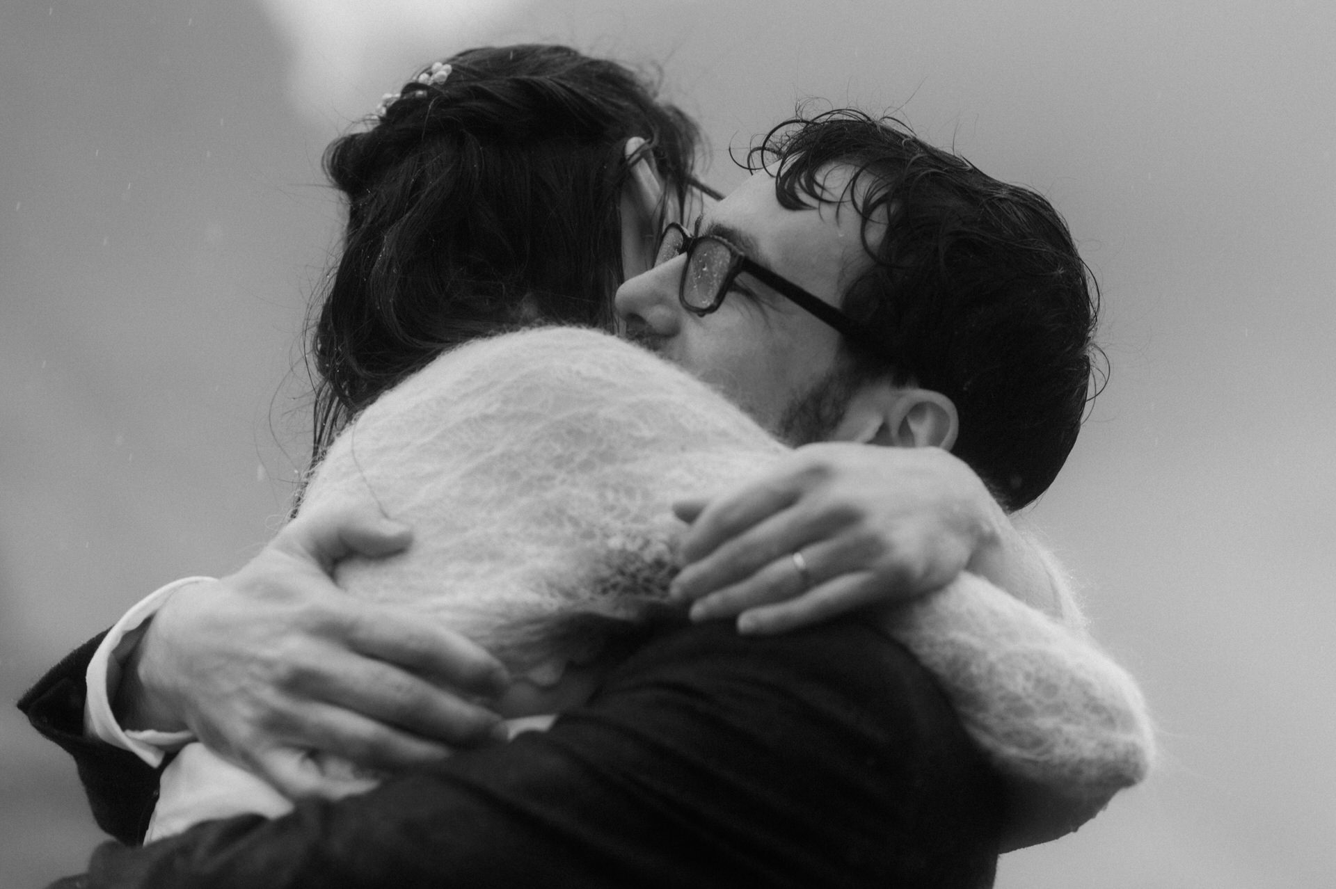 couple hugging on a mountain side in glencoe during there elopement in scotland during a rainy day