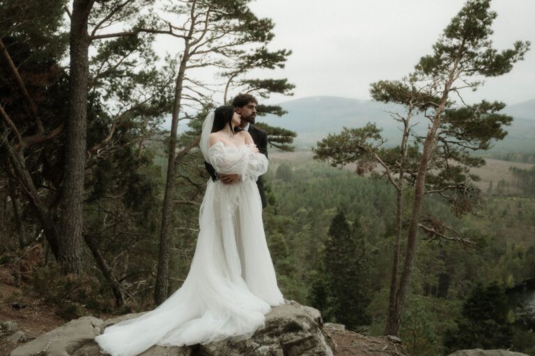 moody elopement in scotland couple standing above woodland in the highlands
