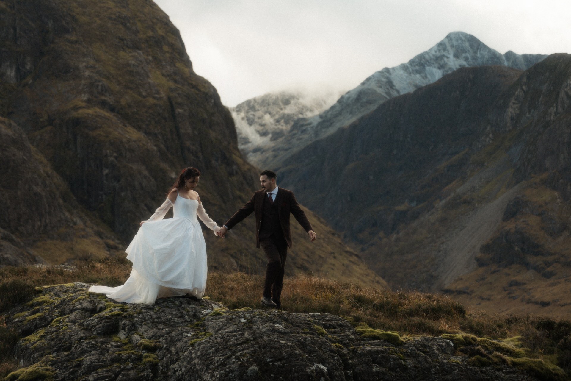 winter elopement in scotland couple walking in the mountains with snow in the background