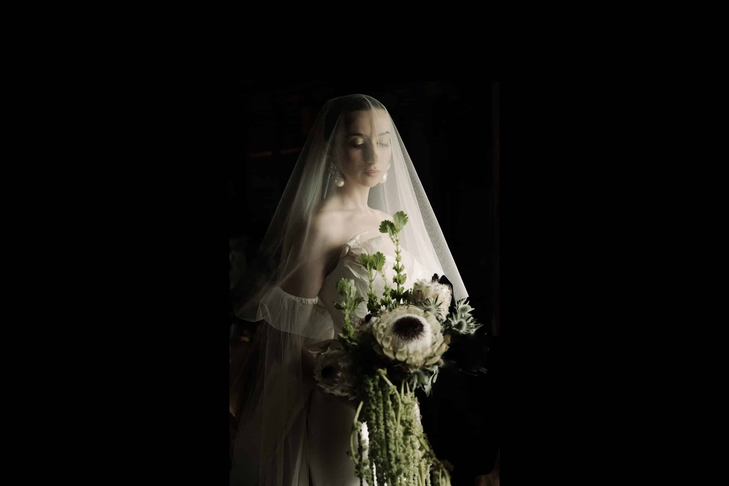 a Scotland bride at her wedding at Borthwick castle standing in sharp light with flowers